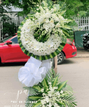 Vòng hoa chia buồn hình tròn tông trắng phối lan và cúc trắng nền lá xanh trang nghiêm