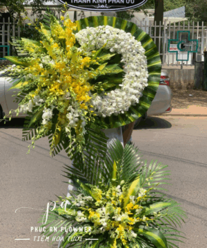 Vòng hoa chia buồn lan trắng phối lan vàng thiết kế tròn nền lá xanh trang nghiêm